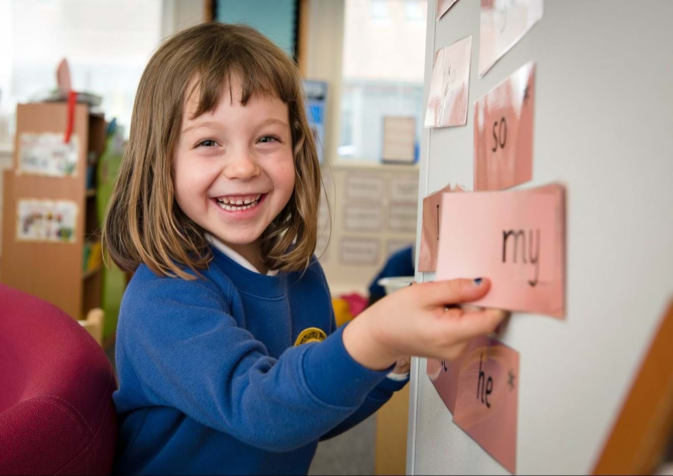 A student smiles while placing a word on the whiteboard
