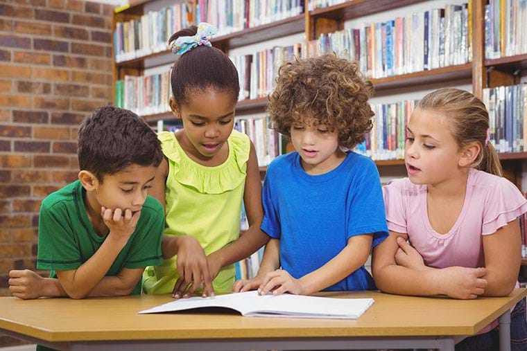 A group of children pore over a book