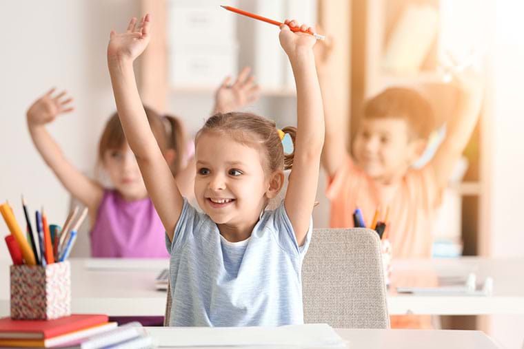 Children in class put their hands up