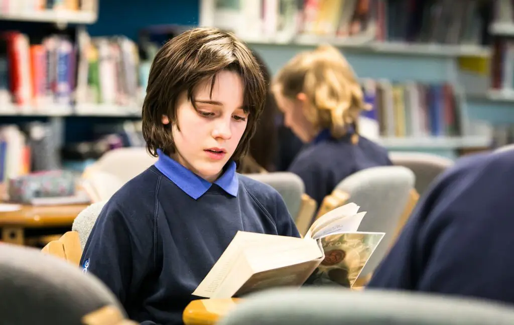 Student reading a book in a school library.
