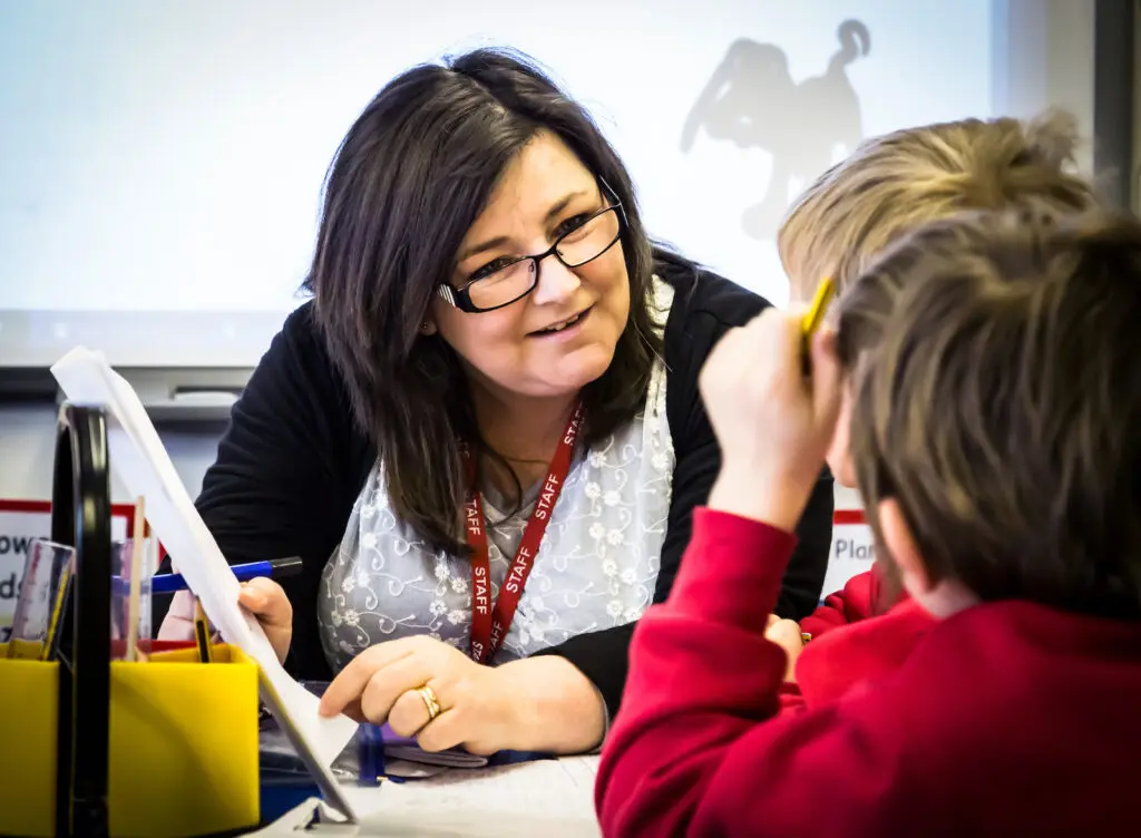 A teacher helping young students in a classroom.